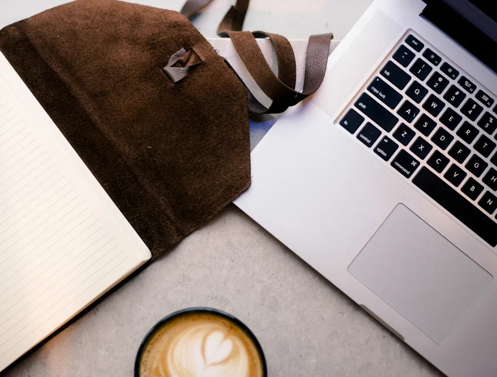 Cuaderno abierto y una taza de café sobre una mesa